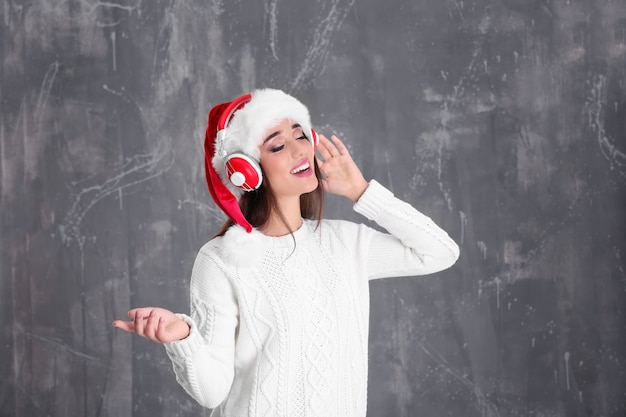 Foto bella giovane donna in cappello di babbo natale che ascolta la musica di natale