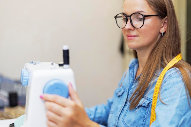 Beautiful young woman sewing clothes using a sewing machine