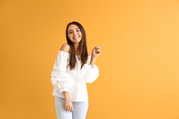 Beautiful young woman showing something on color