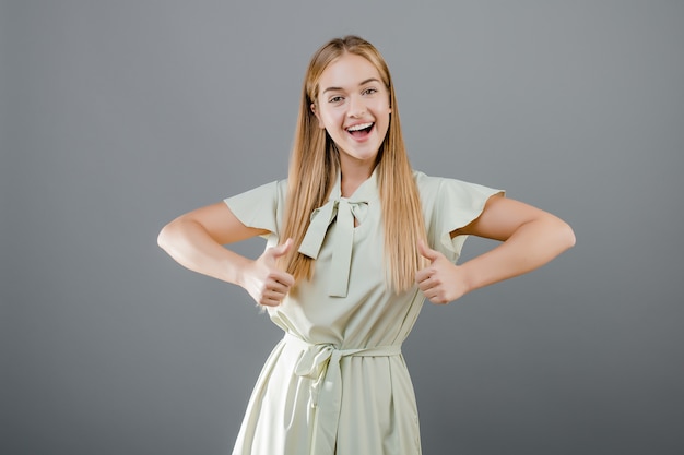 Beautiful young woman showing thumbs up isolated over grey