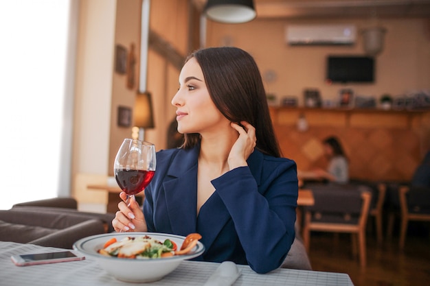 Beautiful young woman sit at table and look to left