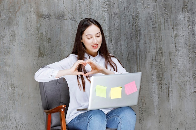 Beautiful young woman sitting on armchair having call with laptop. High quality photo