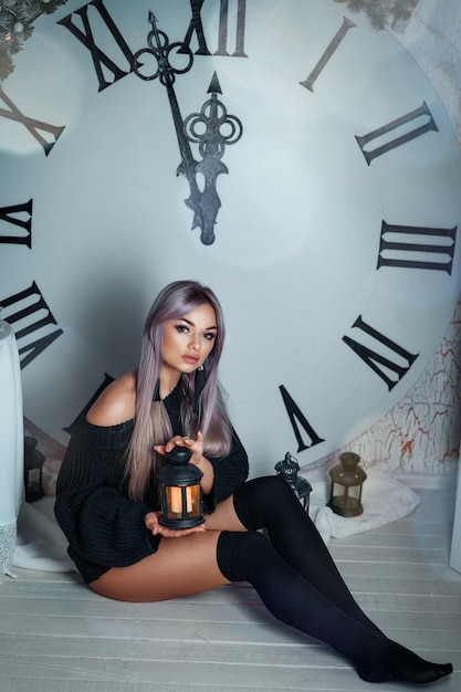 Beautiful young woman sitting on the background of a large clock