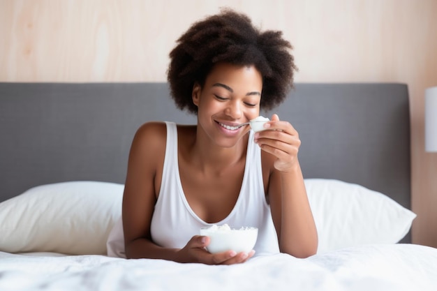 Красивая молодая женщина сидит в постели и ест миску йогурта, созданного с помощью генеративного искусственного интеллекта.