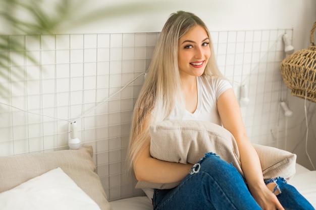 beautiful young woman sitting on bed with a pillow