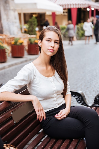 Beautiful young woman sitting on the bench in old town