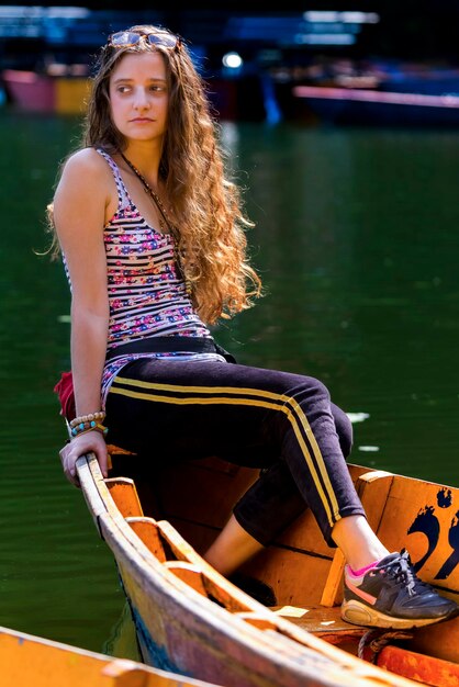 Beautiful young woman sitting in boat on lake