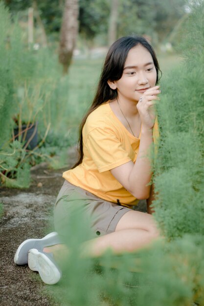 Photo beautiful young woman sitting by plant