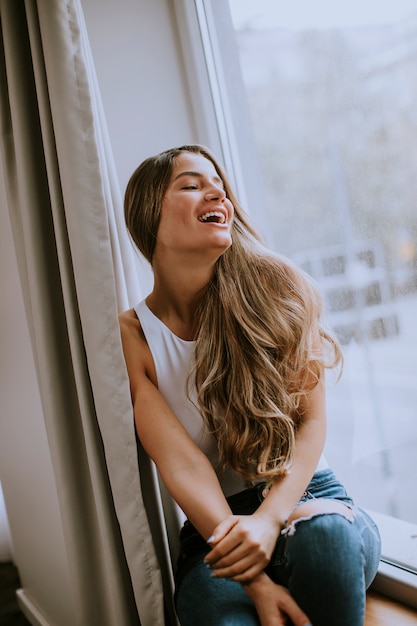 Beautiful young woman sitting by the window