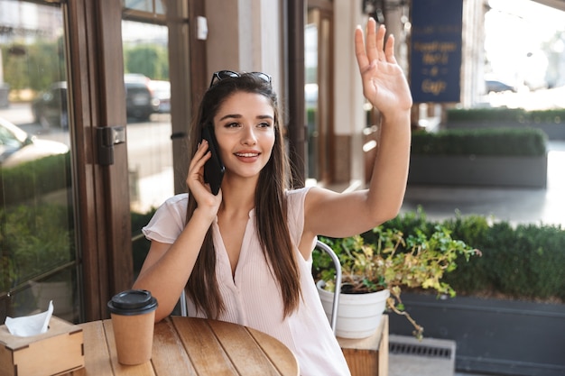 屋外のカフェテーブルに座っている美しい若い女性