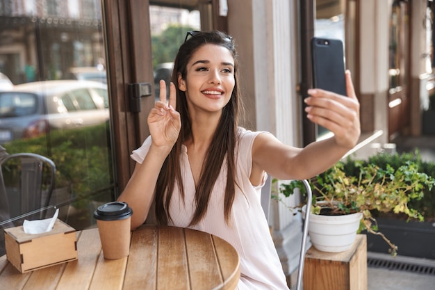 Beautiful young woman sitting at the cafe table outdoors