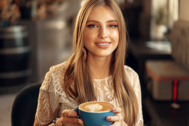 Beautiful young woman sitting in coffee shop enjoying her drink