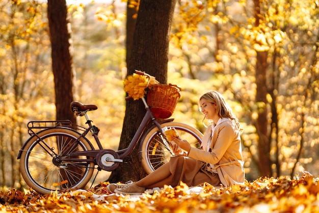 Beautiful young woman sitting on a fallen autumn leaves in a park reading a book Relaxation