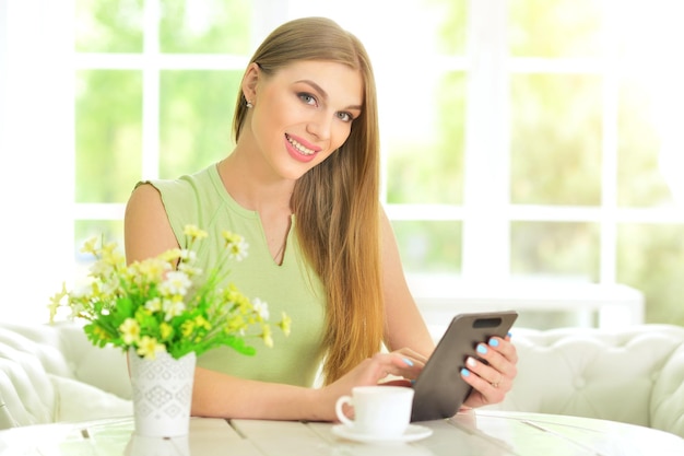 Beautiful  young woman sitting at  table and using  digital tablet