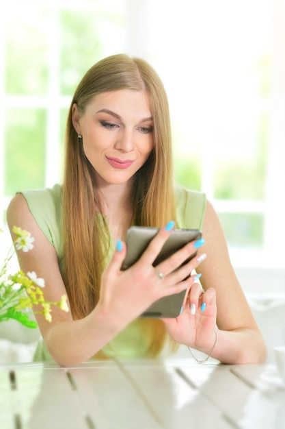 Photo beautiful  young woman sitting at  table and using  digital tablet