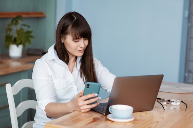 Beautiful young woman sitting at a table with a laptop