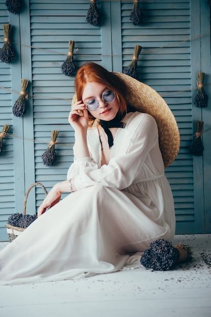 Beautiful young woman sitting with lavender against the blue wall.