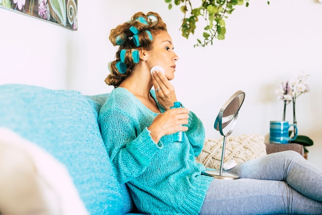 Beautiful young woman in skin care treatment at home sitting on the couch