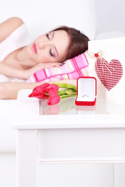 Beautiful young woman sleeping on sofa  near table with gifts and flowers, close up