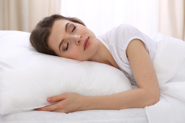 Beautiful young woman sleeping while lying in her bed and\
relaxing comfortably. it is easy to wake up for work or the day\
off. concept of pleasant and rest reinstatement for active\
life.