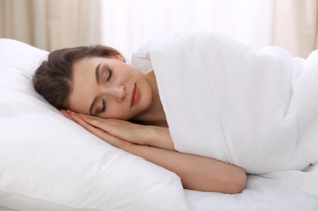 Beautiful young woman sleeping while lying in her bed and\
relaxing comfortably. it is easy to wake up for work or the day\
off. concept of pleasant and rest reinstatement for active\
life.