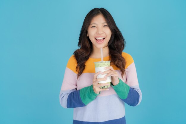 Photo beautiful young woman smiling happily while holding bubble tea in her hand