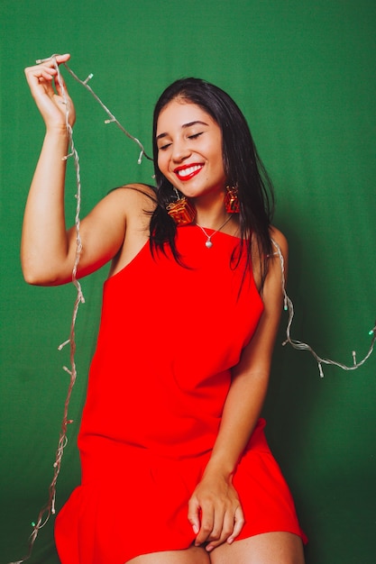 Beautiful young woman smiling and holding christmas lights