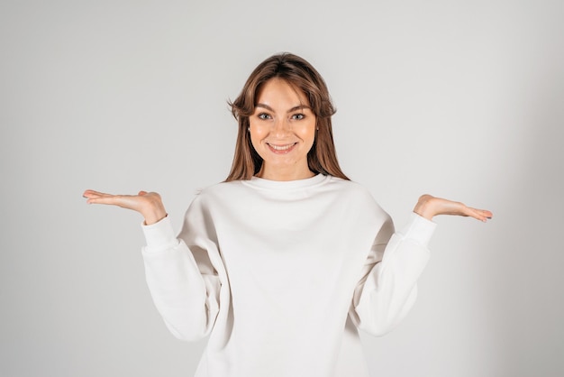 Beautiful young woman smiling and looking to the camera with both hands to the side