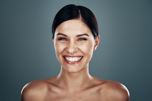 Beautiful young woman  and smiling while standing against grey wall