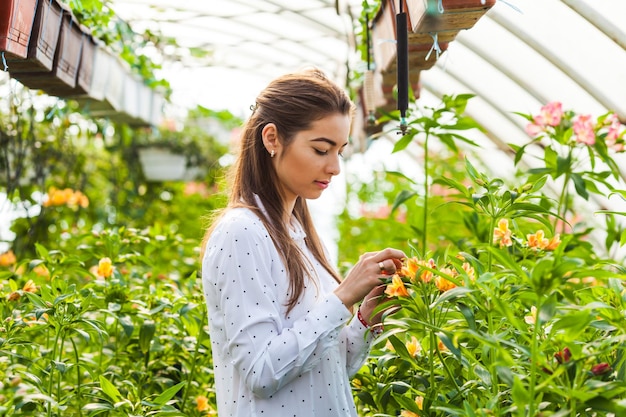 Beautiful young woman smiling while standing in a greenhouse