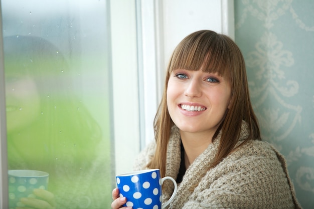 美しい若い女性は茶のカップで笑顔