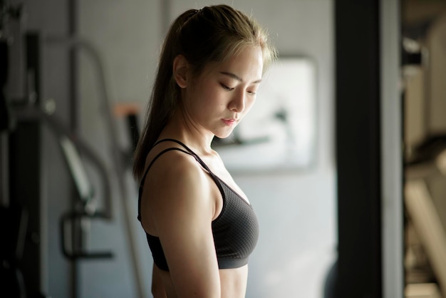 A beautiful young woman in sportswear exercising with dumbbells at the gym, concept of healthy lifestyle, sports, training, wellness, and sport