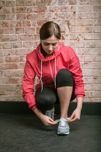 Beautiful young woman in sportswear tie shoelaces