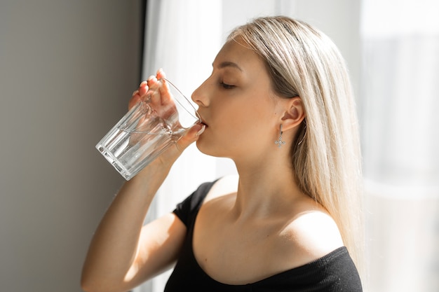 水のガラスとスポーツウェアの美しい若い女性