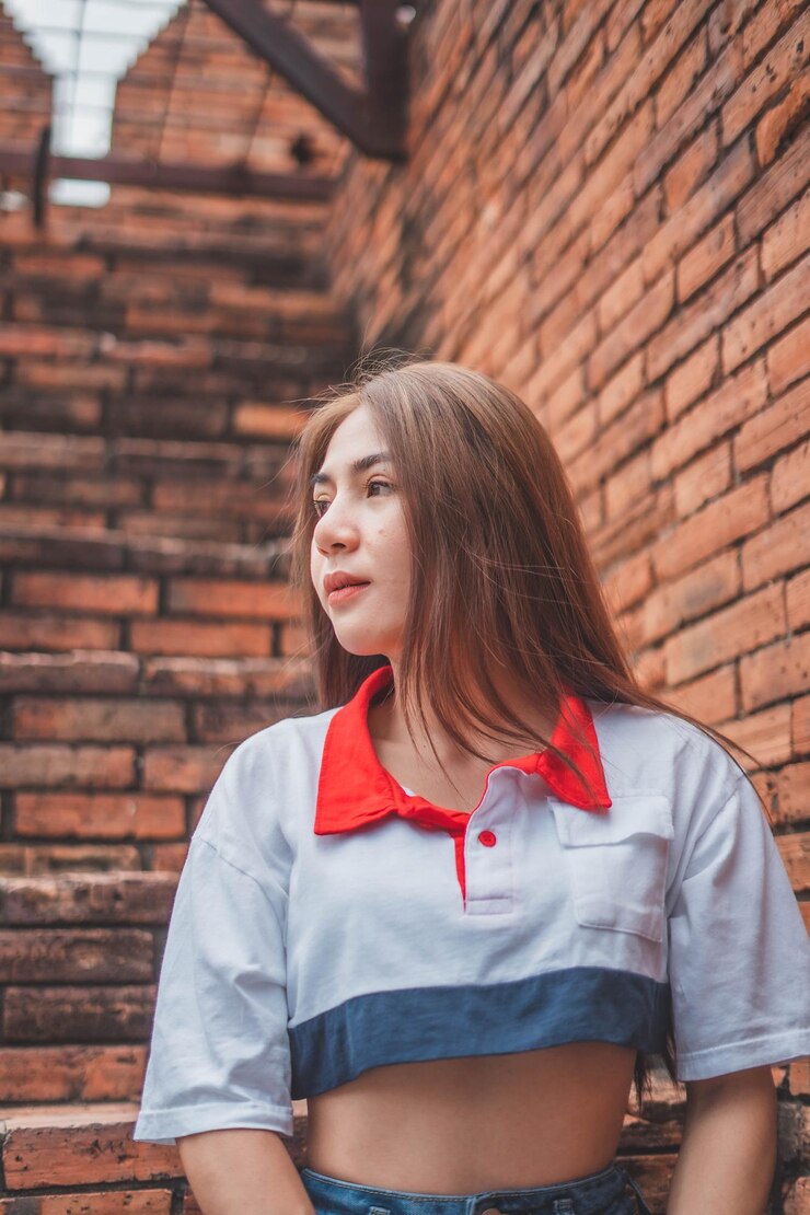 Фотография красивая молодая женщина, стоящая у кирпичной стены.