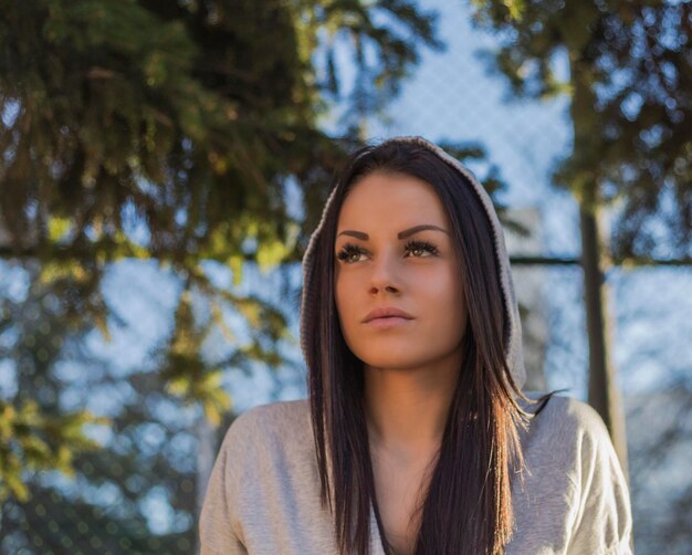 Beautiful young woman standing against fence