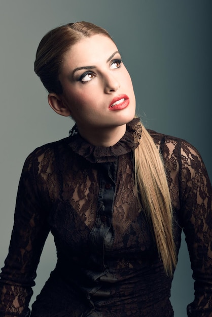 beautiful young woman standing against gray background