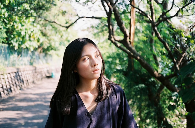 美しい若い女性が木のそばに立っています