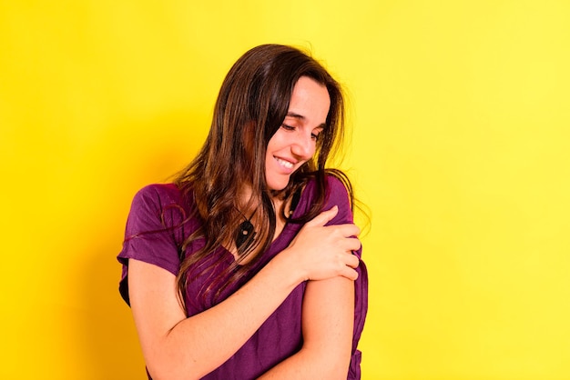 Beautiful young woman standing against yellow background