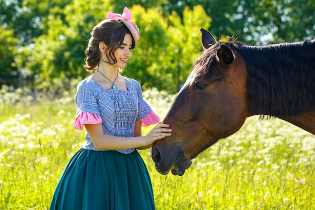 Beautiful young woman standing next to a horse in nature.
