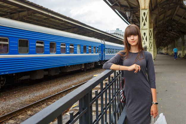 鉄道駅旅行の概念のプラットフォームの上に立っている美しい若い女性。