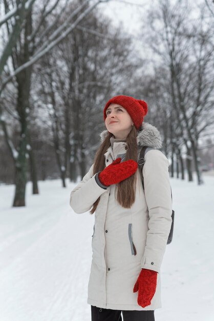 겨울 숲에서 눈 덮인 나무 사이에 서 있는 아름 다운 젊은 여자. 수직 프레임.
