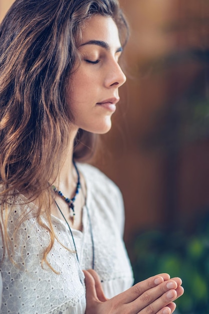 Beautiful young woman standing with her eyes close meditate while practicing Yoga with hands in prayer position