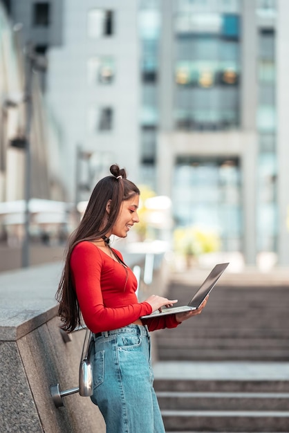 Beautiful young woman on the street using laptop