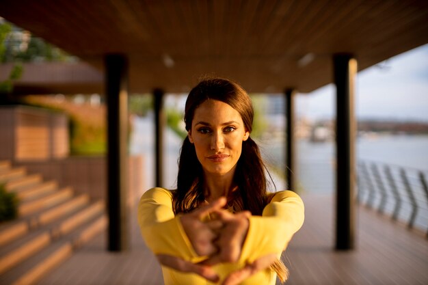 Beautiful young woman stretching on the riverside