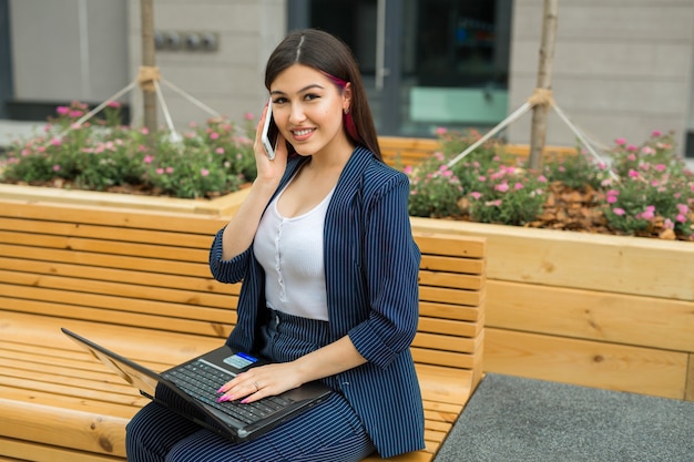 beautiful young woman in suit with laptop and phone