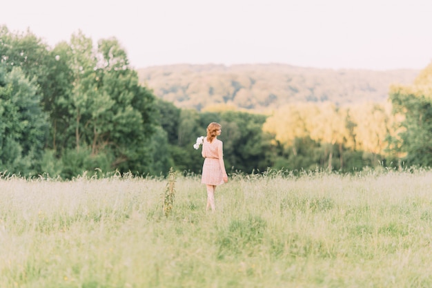 Beautiful young woman in a summer dress with peonies