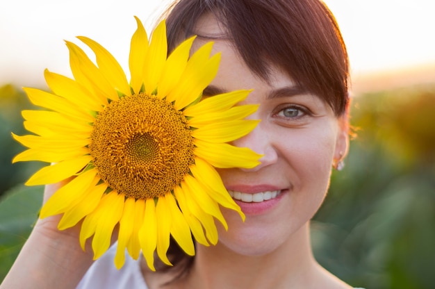 Beautiful young woman in a sunflower field. Portrait of a young woman in the sun. Pollen allergies concept. Outdoors lifestyle happiness