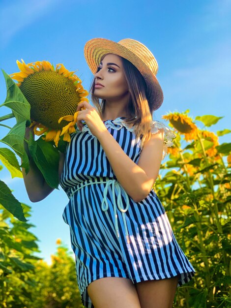 Beautiful young woman in sunflower field on summer day