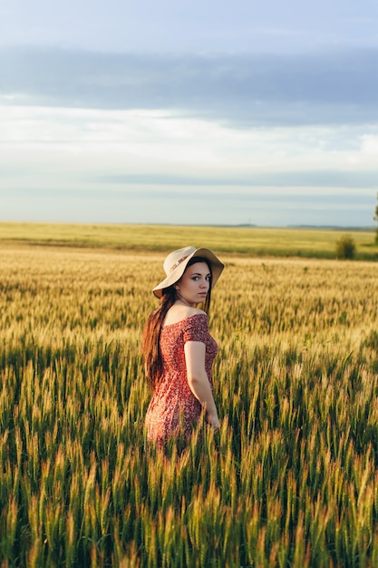 Beautiful young woman at sunset in the field